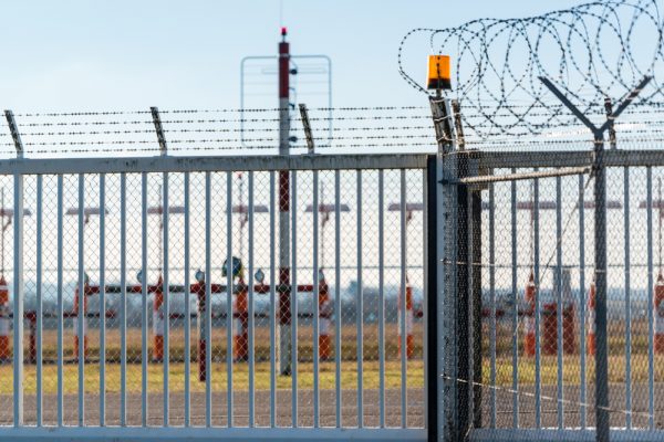 security fence around airport with runway lights in the background